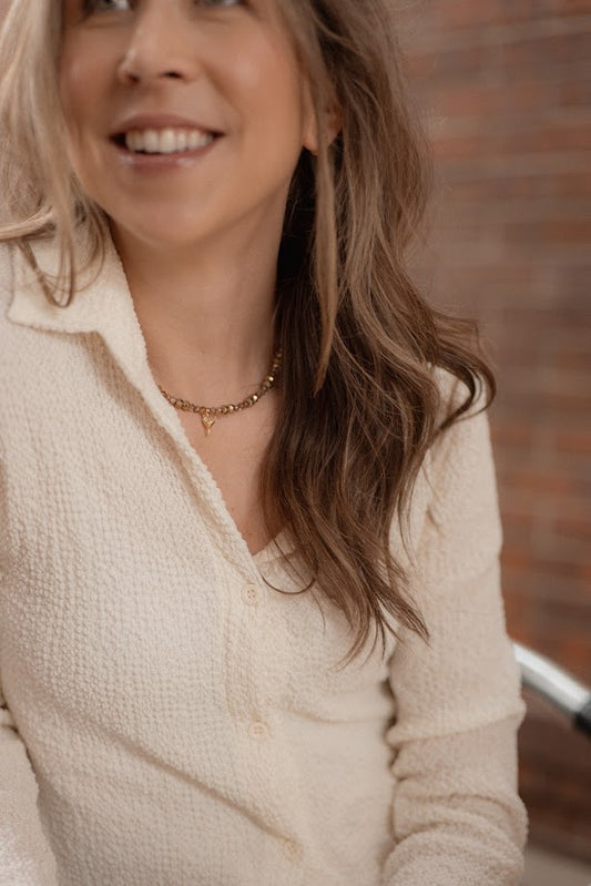 Woman wearing a beige sweater with a blurred brick wall background