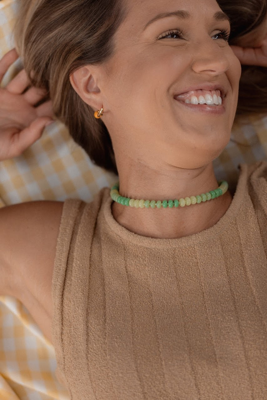 Woman wearing a green beaded choker with a blurred background